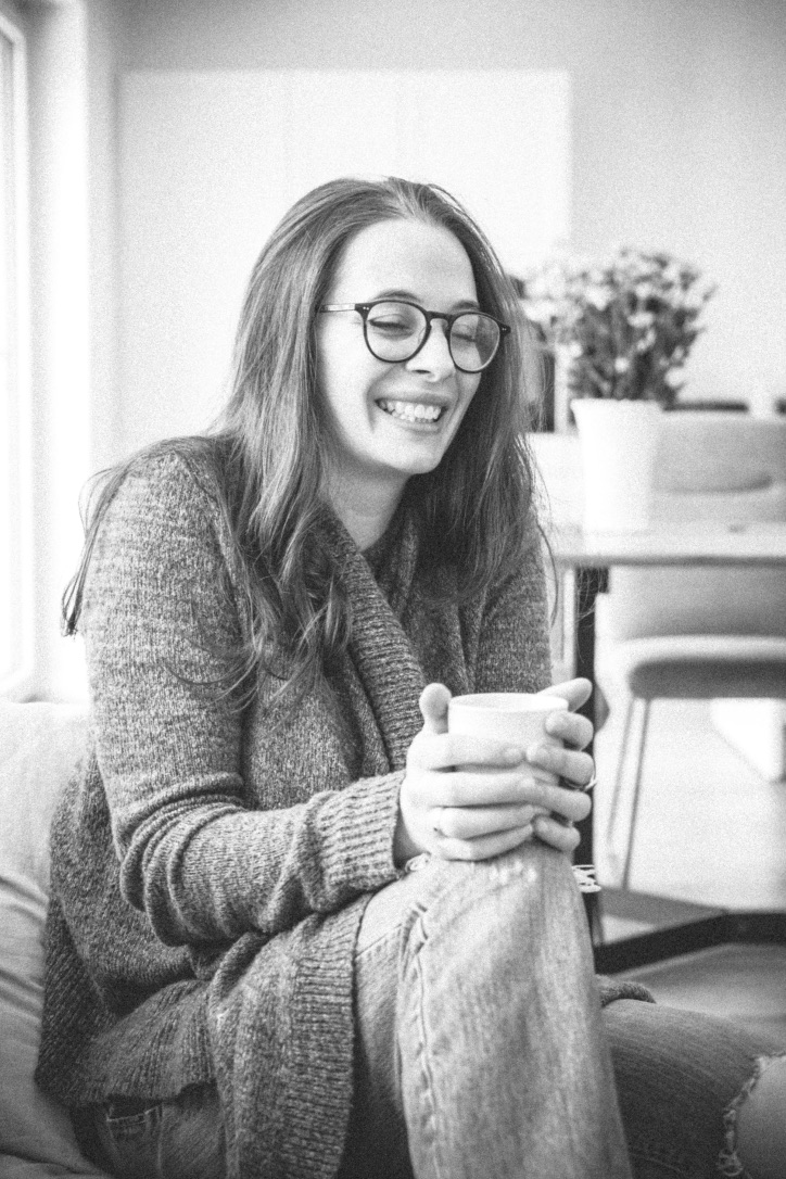 Isabel Zadra sitzt entspannt mit einer Tasse in der Hand und lacht